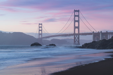 Classic panoramic view of famous Golden Gate Bridge seen from scenic Baker Beach in beautiful golden evening light on sunset with blue sky and clouds in summer, San Francisco, California, USA