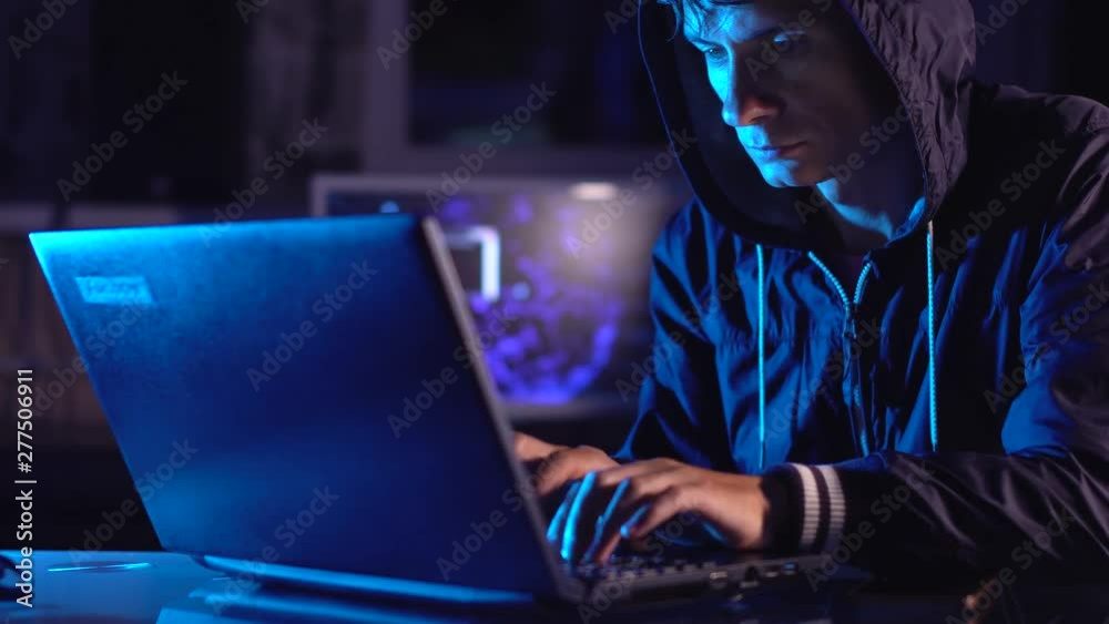 Wall mural hacker typing program code while committing a cybercrime hacking a system firewall in the dark under