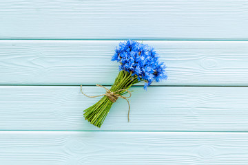 Bouquet of blue cornflowers on mint green wooden background top view mockup
