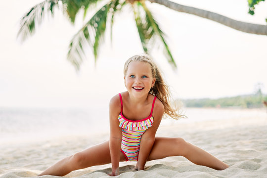 Happy cute child playing on sandy beach under palm tree