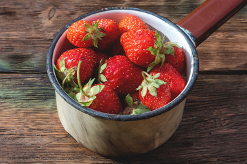 Strawberry berries in a bowl on garden table background.