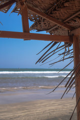 Beautiful dry branches of palm trees on the roof against the backdrop of the beach. Ocean and sea in summer in the rays of the sun.