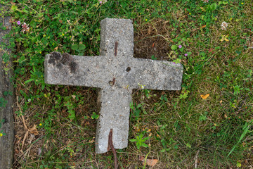 Old concrete cross that has fallen in the grass