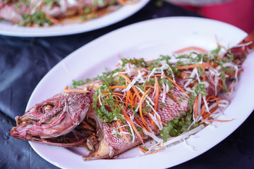 Fried sea fish on a white plate. Seafood in an outdoor cafe in Asia. Stock photo