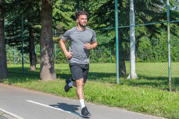 Handsome man running in park with trees in background