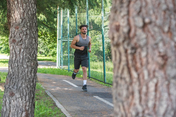 Handsome man running in park with trees in background