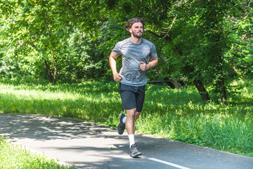 Handsome man running in park with trees in background