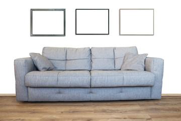 Interior of living room with sofa or couch furniture on wooden floor and three mockup art frames isolated with white wall background