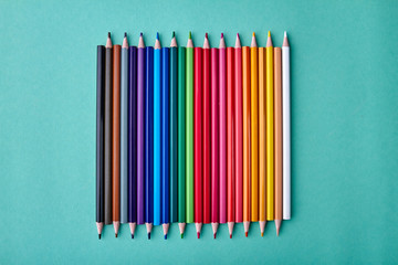 Row of multicolored pencils on color background. Set of colorful pencils on turquoise background....