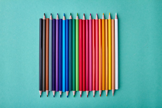 Row of multicolored pencils on color background. Set of colorful pencils on turquoise background. Concept of school supplies.
