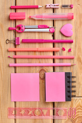 Set of pink stationery on wooden background. School supplies for girl on wooden table. Back to school.