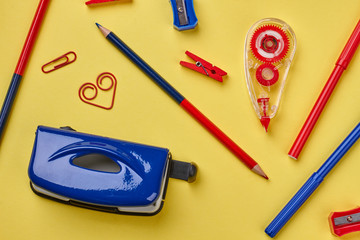Colored school supplies on yellow background. Various stationery items on color background. Back to...