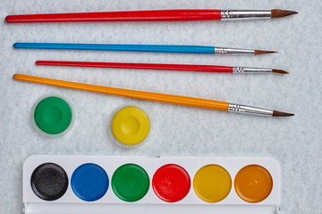 Watercolor palette with paint brushes on white background. Education and creativity concept.