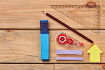 School supplies on wooden background. Marker, adhesive tape, ruler, chalk and sticky note. Back to school.