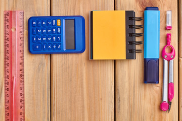 School supplies on desk background with copy space. Blank spiral notebook, calculator and other school items. Space for text.
