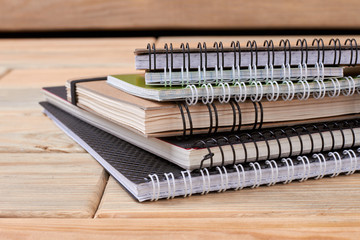 Stack of spiral notebooks on wooden background. Pile of paper notepads with ring binding on wood...