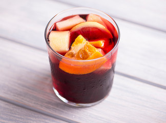 A glass with sangria on wooden table. Typical Spanish drink with wine and fruits.