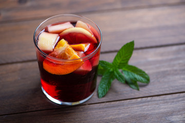 Glass with sangria and mint leaf on wooden table. Typical Spanish drink made with wine and fruits.