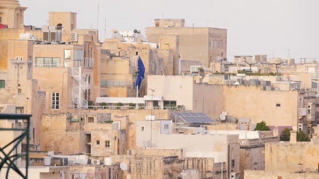 Dense buildings, historic stone houses in heat and dust, Middle Ages, desert, Africa, Malta, EU flag