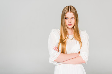 angry girl with crossed arms isolated on grey