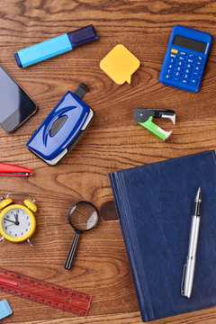 Workplace with different stationery supplies. Notebook, alarm clock, mobile phone, calculator and other school items. Work or education concept.