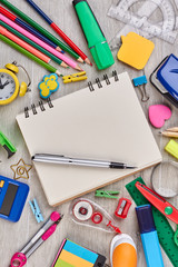 Notebook, pen and office supplies. Blank notepad, pen and various school accessories on wooden...