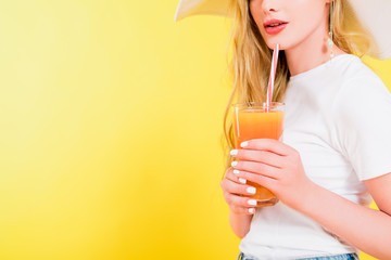 cropped view of blonde girl with cocktail glass On yellow