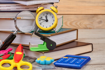 Stack of books, alarm clock and various school supplies. Still life with books and alarm clock. Back to school concept.
