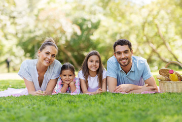 family, leisure and people concept - happy mother, father and two daughters laying on picnic...