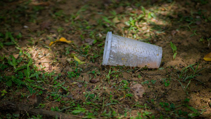 Plastic cup on the ground. Pollution of the environment. Garbage in the park.