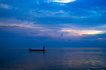 Minimal silhouette fisherman on the lake with twilight sky.