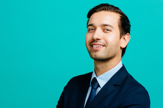 Portrait of a confident, smiling man in suit and tie, isolated on blue studio background