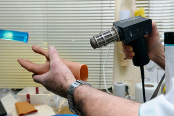 Worker’s hands drying a part of an artificial limb – glow- with a blow dryer