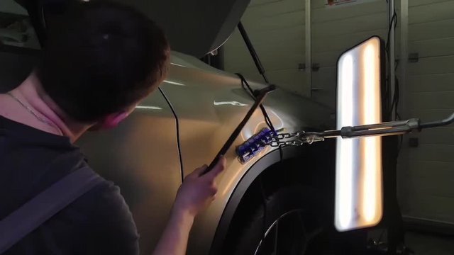 Paintless Dent Repair Removal. Tap Down Tools Dent Rubber Hammer Auto Body. The guy knocks with a hammer on the car to align the dent on technology PDR.