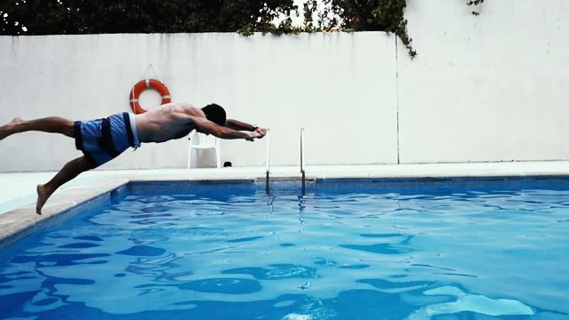 Fit caucasian man dives head first into the pool