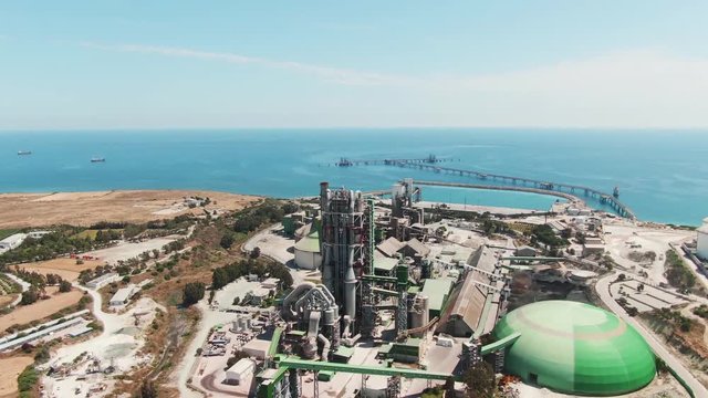 Flying over large construction of fuel power plant on the island. Drone view of the factory buildings in the industry area at Mediterranean sea. Cyprus, Europe.