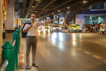 European man stops a taxi on the street of Bangkok in Thailand