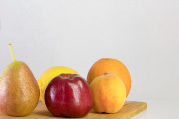 red apple, pear, lemon, orange, peach on white background, copy space