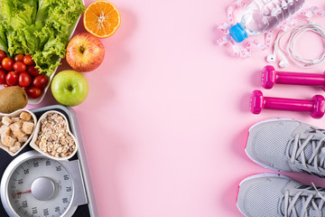 Healthy lifestyle, food and sport concept. Top view of athlete's equipment Weight Scale measuring tape pink dumbbell, sport water bottles, fruit and vegetables on pink pastel background.