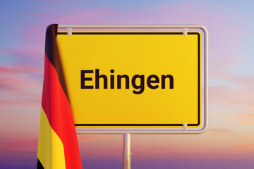 Ehingen. Gelbes Schild/Ortsschild. Flagge von Deutschland hängt darüber. Himmel mit Sonnenuntergang oder Sonnenaufgang