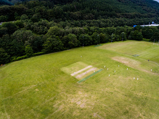 Aerial view of players, playing a game of Cricket on a Welsh Park Pitch in the summer
