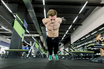 Fototapeta na wymiar Clap pushup fitness man doing plyometrics push-up exercises explosive workout for muscles training. Athlete working out on gym floor indoor.
