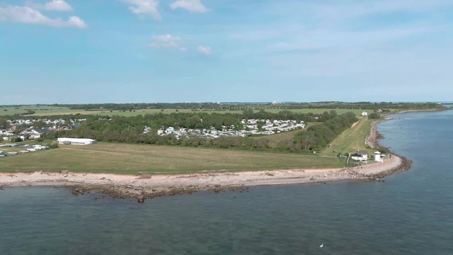 droneshot of a campsite at the beach, with lighthouse on a sunny day