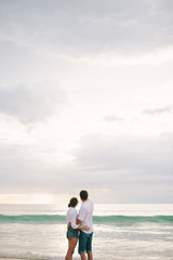 Fototapeta premium A man hugs a woman. They stand and look at the sea. Solitude together.