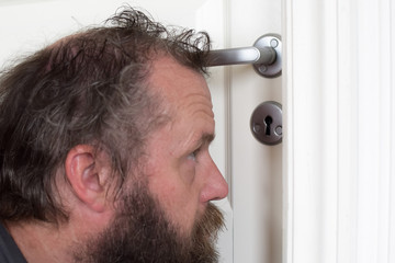 Obraz premium European 50 years old looks into the keyhole. Peeping man. Selective focus