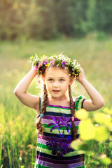  little girl in a wreath of wild flowers in summer