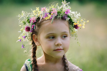  little girl in a wreath of wild flowers in summer