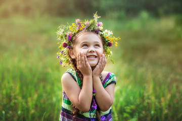  little girl in a wreath of wild flowers in summer