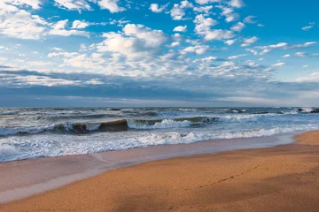 Papier peint photo Vagues de l'océan A beach with golden sand, small waves and a beautiful dramatic sky  © Vastram