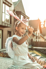 Expressive pretty princess in a white dress playing in front of the house